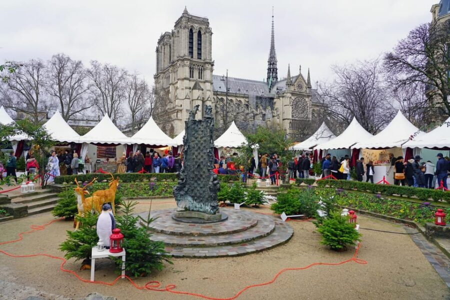 Paris: Christmas Market Guided at Notre Dame & Food Tasting - Glowing views and a festive Santa’s stall photo moment